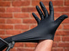 Black glove being stretched out in front of a brick wall