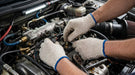 Mecanics working on a car engine with gloves on-