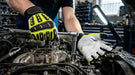 Person working on a car engine with tools and gloves in a garage setting
