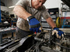 Mechanic working on a car engine in a garage wearing a Tuff Gard Cowgrain Mechanic Glove – Blue & White