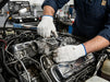 Mechanic working on a car engine in a workshop wearing Tuff Gard Nylon Knitted Glove – Bleach White, 13 Gauge 